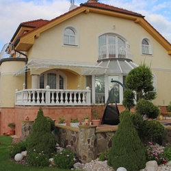 Prikrytie terasy rodinného domu kovaným prístreškom v bielej farbe