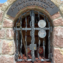 Forged monument of Saints with characteristic features:A staff, a medal