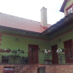 Pohľad na rodinný dom s kovaným prístreškom a zábradliami s dubovým vzorom vyrobenými v UKOVMI Pohľad na rodinný dom s kovaným prístreškom a zábradliami s dubovým vzorom vyrobenými v UKOVMI