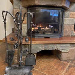 An artistic fireplace tool set with the conifer theme for pleasant autumn and winter evenings by a fireplace