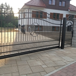 Posuvná kovaná brána s bránkou v jednoduchom štýle pri rodinnom dome Posuvná kovaná brána s bránkou v jednoduchom štýle pri rodinnom dome