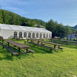 Garden tables and benches on a grassy area for visitors to relax and dine