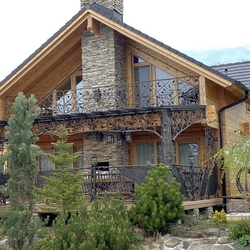 Forged patio roofing, railings with flower pots, outdoor lamps and luxury garden furniture on the terrace of the cottage 